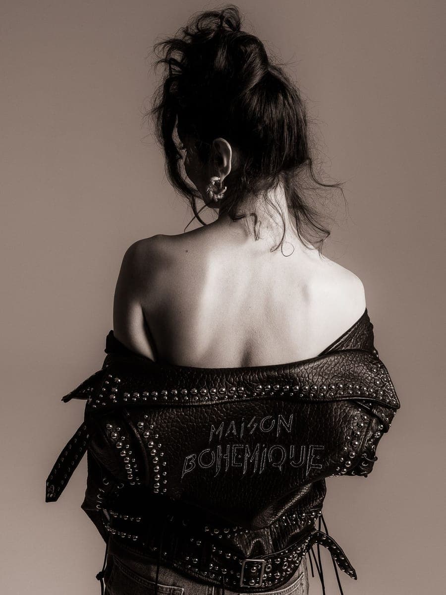 Bare-backed model with pinned-up hair wearing a studded leather jacket off the shoulders