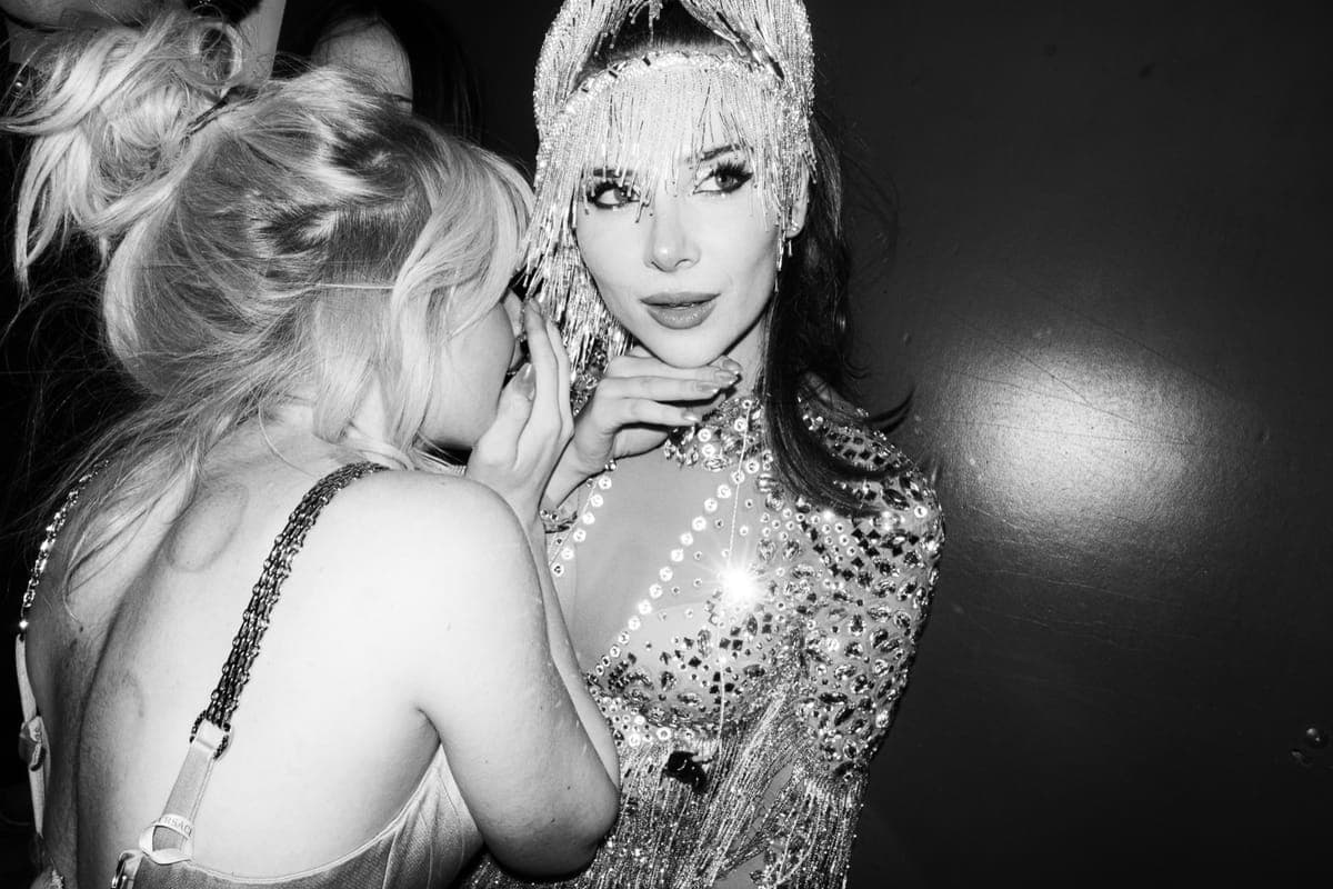 Two women in embellished evening wear at a party, one in a beaded headdress