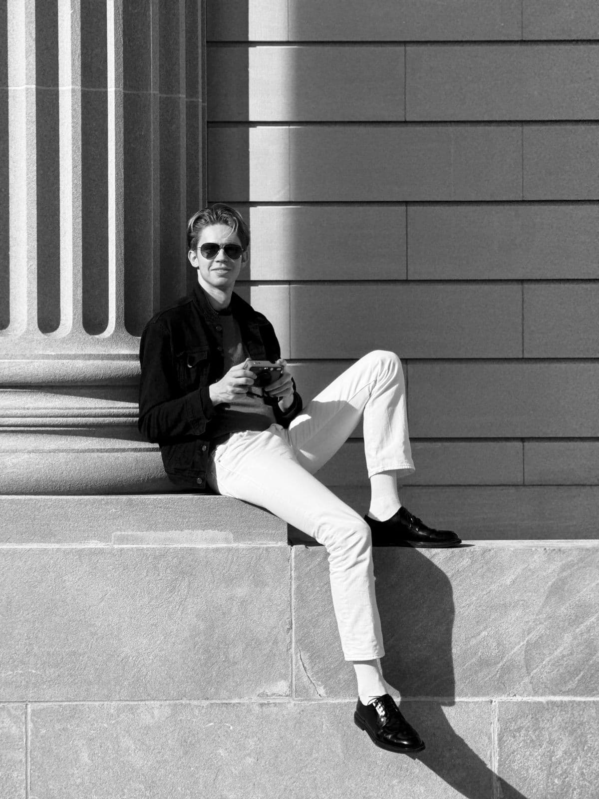 Daniel Grand seated outdoors in sunglasses and a dark jacket
